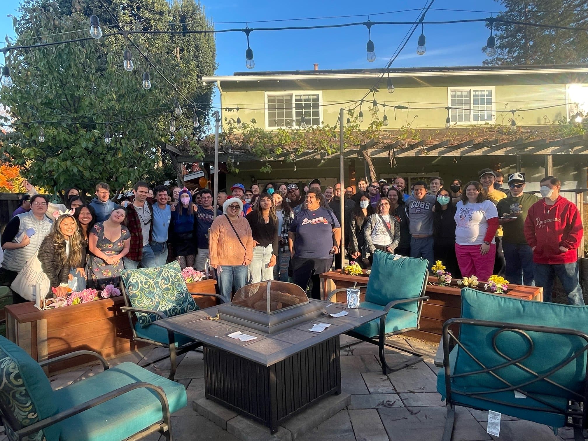 All the Best Buddies members (about 50 people) are huddled in a group and looking at the camera. In the foreground, four lawn chairs and a table are visible.